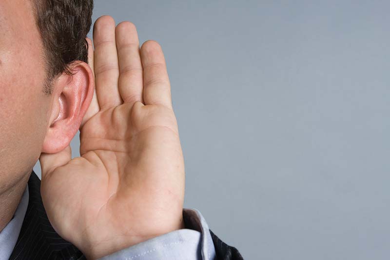 Caucasian man with hand cupped on ear listening